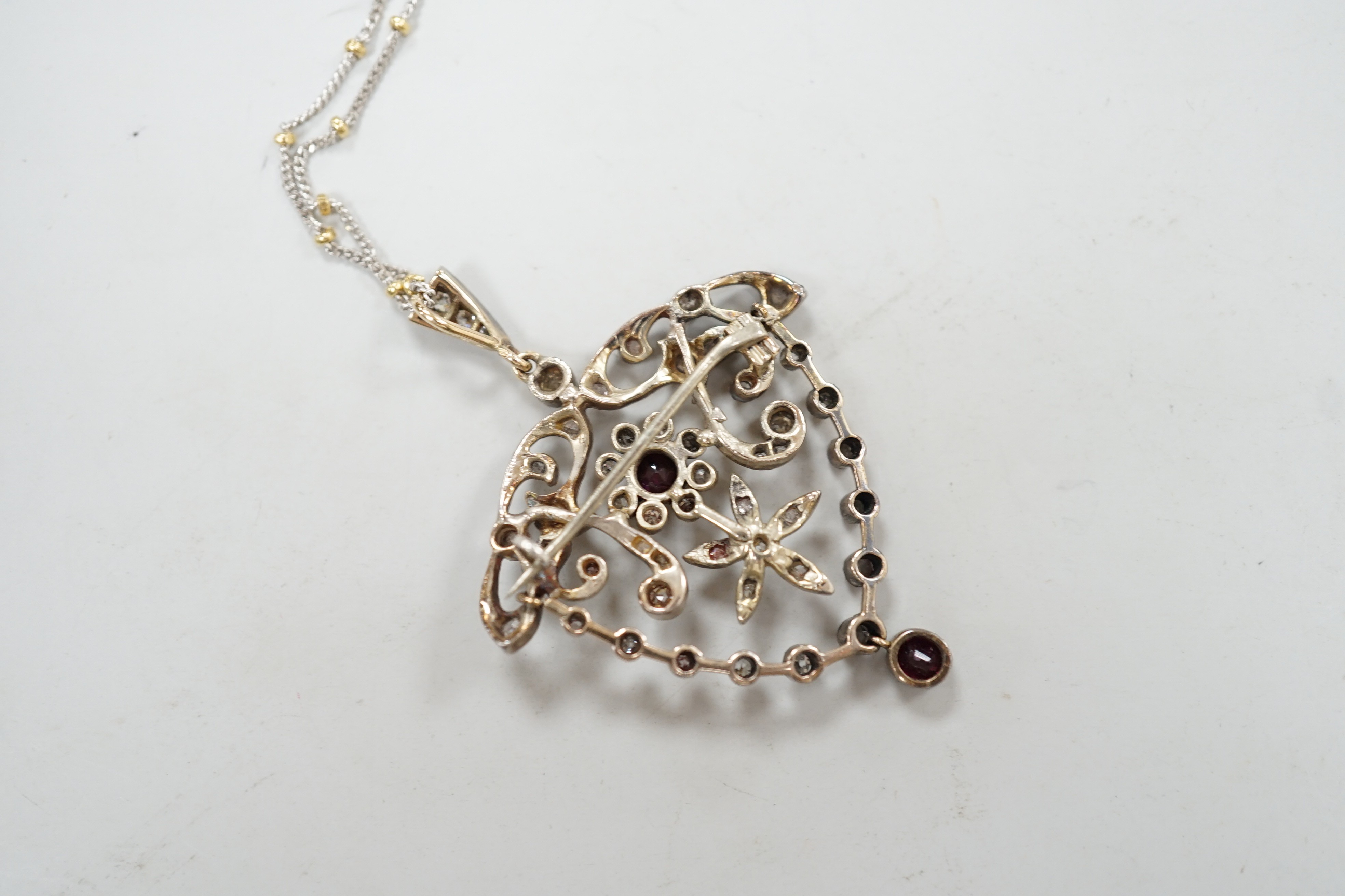 A yellow and white metal, ruby and diamond cluster set drop pendant brooch, 49mm, on an 18ct gold chain, 42cm, gross weight 11.5 grams.